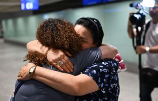 Eine junge Frau umarmt ihre Mutter nach der Heimkehr