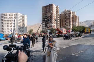 Iranische Journalistinnen und Journalisten vor einem beschädigten Gebäude in Teheran