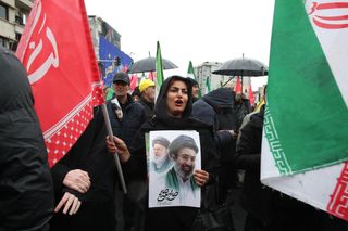 Frau mit Plakat von Ali und Mojtaba Khamenei