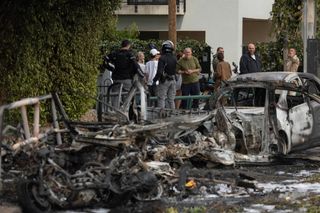 Menschen beobachten Unglücksort, nach dem Einschlag eines Geschosses nach einem iranischen Angriff auf Tel Aviv (März 2026)