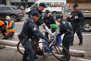 Police arrest a protester in a bike lane as workers begin to remove the lanes along Bloor Street West in Toronto on Wednesday, Oct. 14, 2026. THE CANADIAN PRESS/Arlyn McAdorey