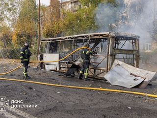 Einsatzkräfte der Feuerwehr löschen einen brennenden Bus nach einer russischen Attacke.