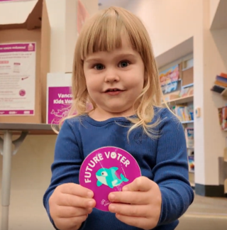 A child holds up a "future voter" sticker in this image shared by the city.