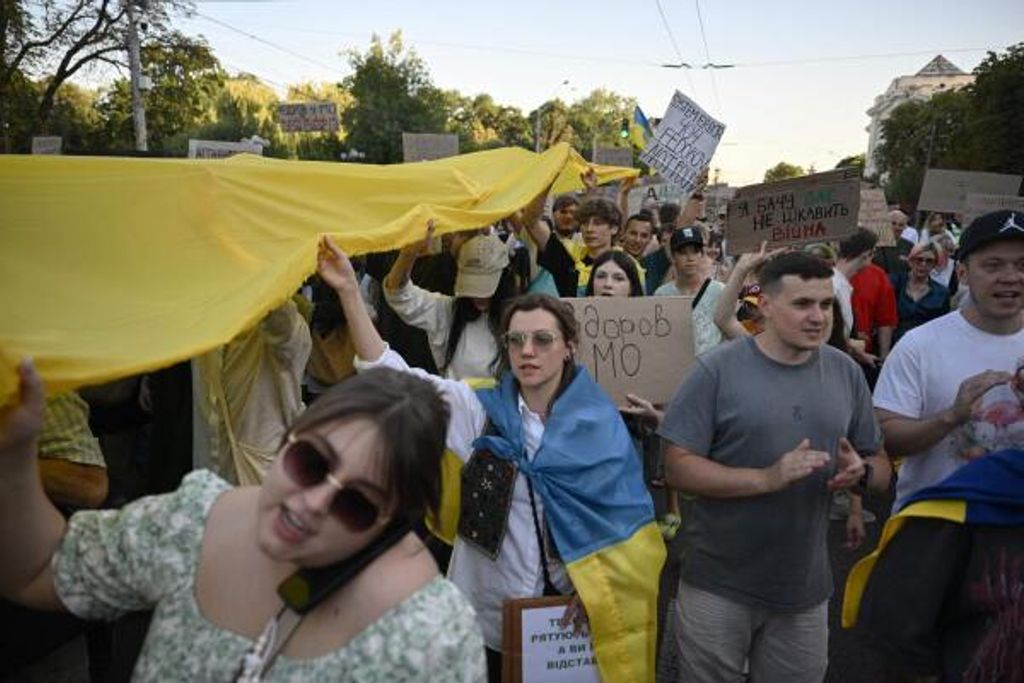 Demonstranten tragen am 31. Juli 2026 in der Kyjiwer Innenstadt eine riesige ukrainische Flagge und Plakate bei einer Demonstration mit der Forderung nach der Wiedereinsetzung des Verteidigungsministers Mychailo Fedorow.