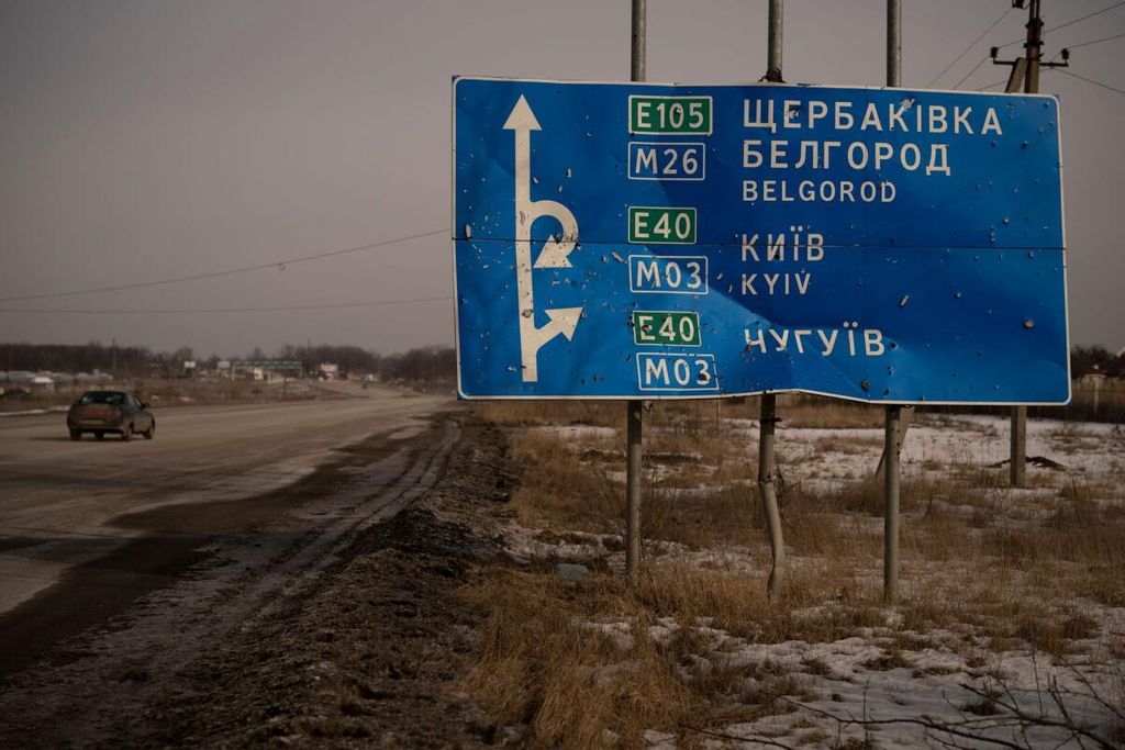 Ein Auto fährt in der Ukraine an einem von Kugeln und Granatsplittern beschädigten Straßenschild auf der Straße zur russischen Stadt Belgorod vorbei (Archivfoto).
