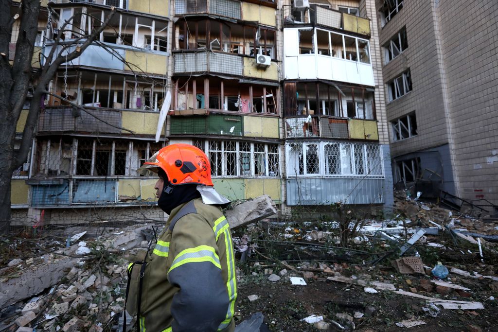 Ein Feuerwehrmann steht vor einem beschädigten Wohnhaus in Kyjiw.