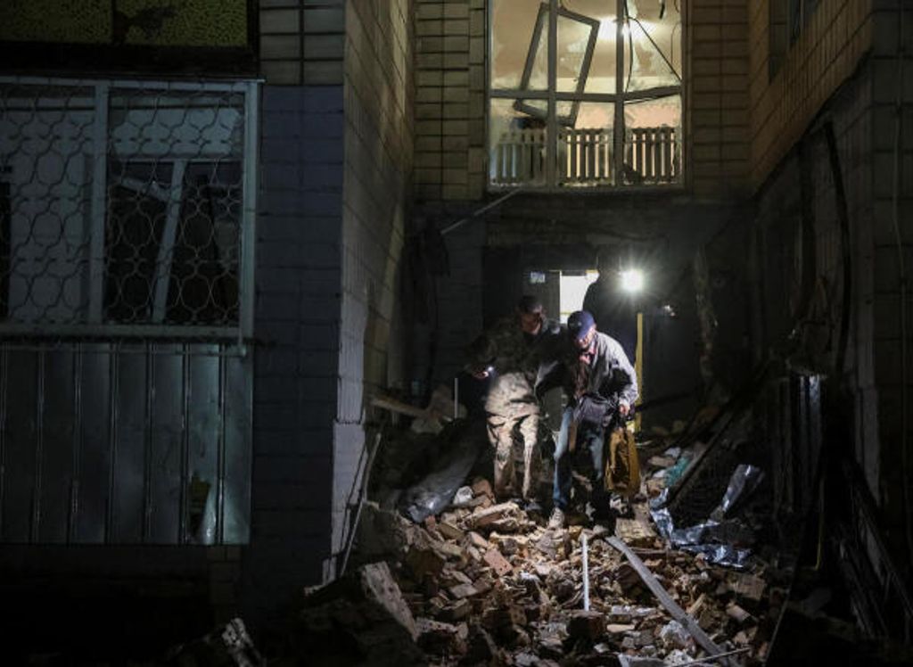 Freiwillige evakuieren einen Bewohner aus einem Wohnhaus, das von einem russischen Raketenangriff getroffen wurde.